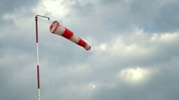 风袜指机场跑道上的风向指示器显示风对多云的蓝色天空的方向和力量