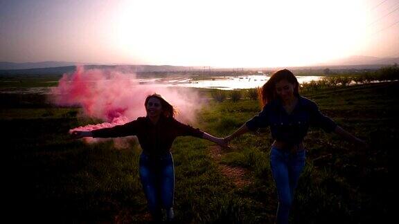 两名年轻女子拿着一枚粉色烟雾弹在空中转圈慢镜头