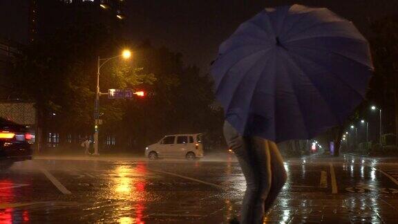 慢镜头:台风期间人们撑着雨伞挣扎着过马路