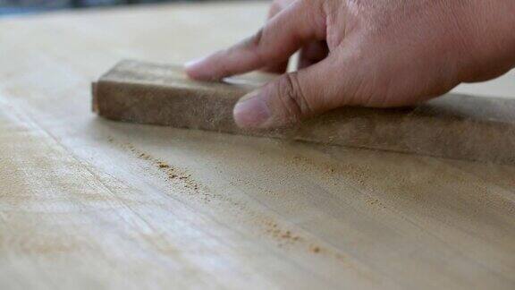 木匠用砂纸和自然阳光打磨木桌