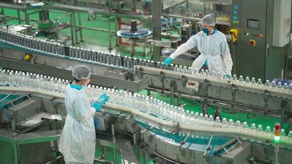 2名亚洲华人水厂生产线工人携带个人防护用品日常检查水瓶工作