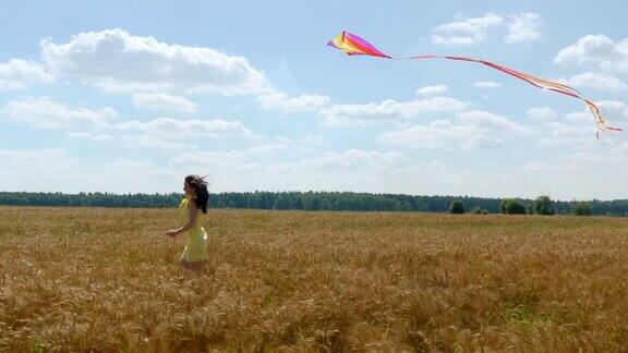 阳光明媚的日子里快乐的女人牵着风筝在麦田里奔跑