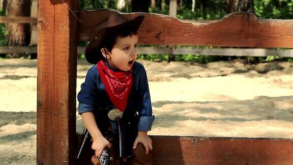 严肃的小牛仔坐在木篱笆上