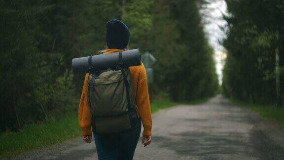 近距离的女人背双肩包走在秋天的森林自然景观旅行天气树户外树林慢动作