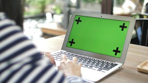 女人打字和看着绿色屏幕的笔记本电脑