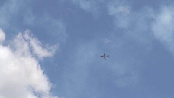 明亮的蓝天下一架商用飞机在稀疏的云层上高高地飞行宽体飞机在高空飞行