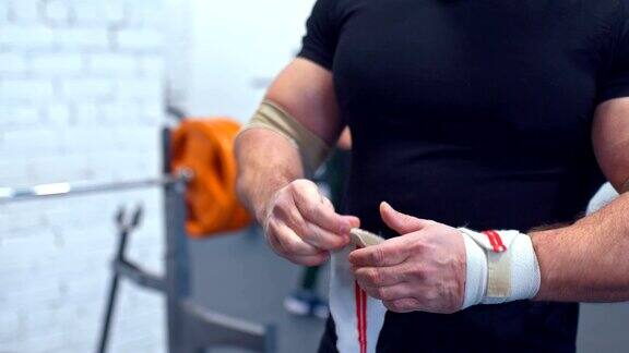 重量级选手用弹性绷带包扎手腕准备运动在健身房训练特写