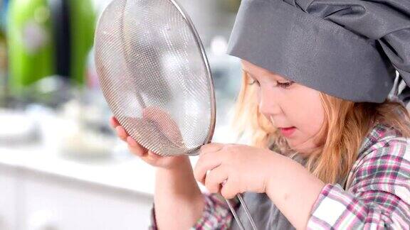 小女孩打扮成厨师在玩筛子