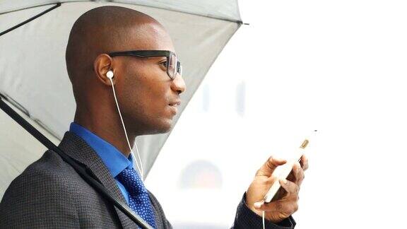 非洲黑人秃头商人使用耳麦耳机的移动电话