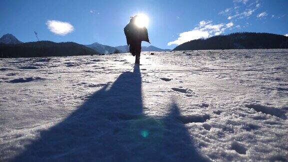 在阳光明媚的冬日一个面目全非的家伙在雪地上慢跑年轻人在白雪覆盖的草地上奔跑背景是阳光和蓝天假日或假期后视图慢动作