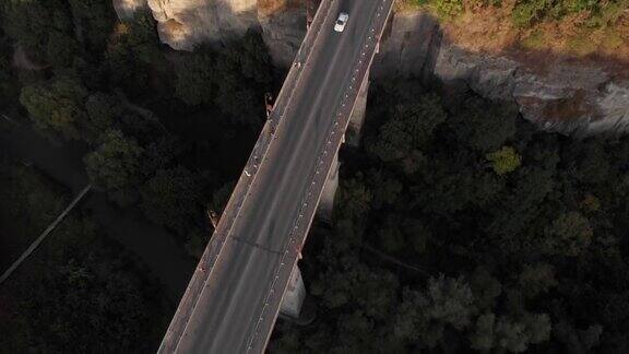 在深峡谷悬崖上的古老乌克兰欧洲小镇Kamianets-Podilskyi公路桥的航拍日落的交通