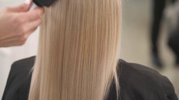 一个近距离的金发的头发梳由一个排气发刷长度摄像机慢慢地上下移动