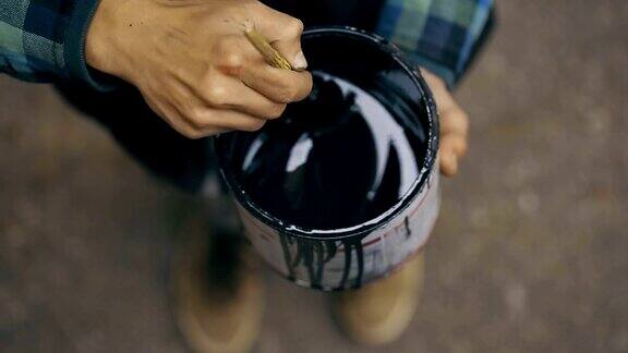画家在街上用罐子搅拌一种油漆