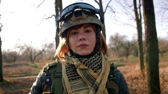 年轻漂亮的红头发女人穿着军装手持步枪在战场地区