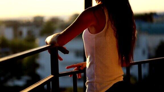 年轻女子在阳台上看日落中景