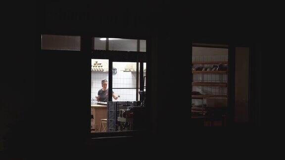 从黑暗的外面可以看到女面包师在工作