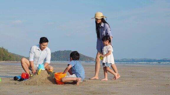 亚洲家庭快乐的玩在沙滩上堆起一堆沙子在夏天一起度假家庭旅行4k决议