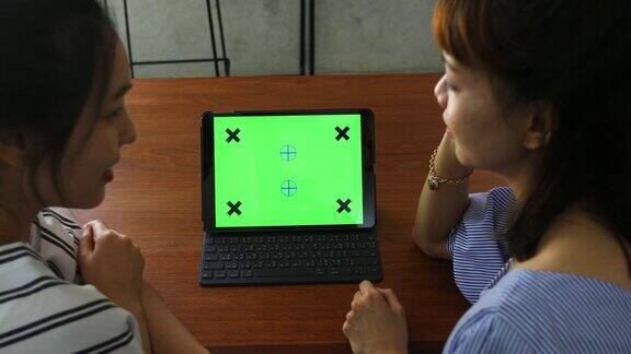 两个女人在用平板电脑的绿色屏幕