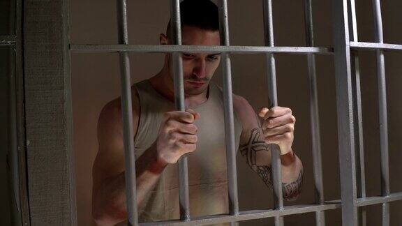 4K朵莉:男囚犯在监狱的牢房里握着栏杆