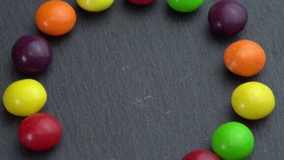 彩色糖果在黑色背景上旋转手拿一颗糖果彩色糖果