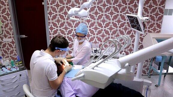 一位年轻的牙医和他的助手在工作柜中治疗病人