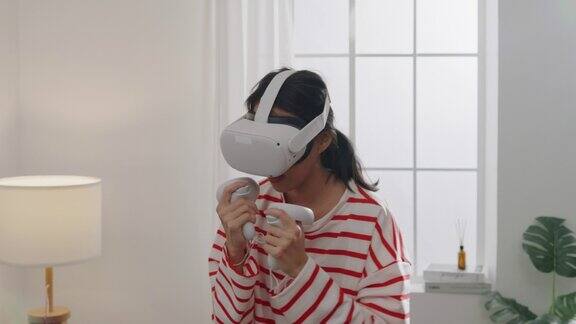 年轻女子戴着VR头戴式设备在家中客厅体验模拟数字世界拳击姿势玩动作模拟游戏手机app