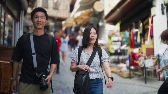 一对年轻的旅游夫妇漫步在历史悠久的小镇和集市上