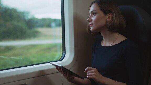 在《行进中的火车》中一名女子在窗口旁使用平板电脑