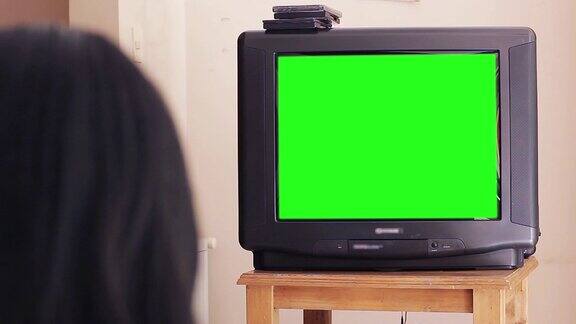 看绿屏幕旧电视的女人