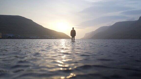 一个人站在浅湖的日出