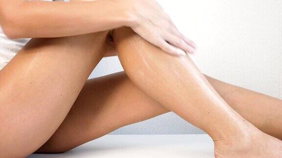 拥有完美身体的女人在她的腿上涂抹清爽霜或身体乳液概念脱毛护肤化妆品
