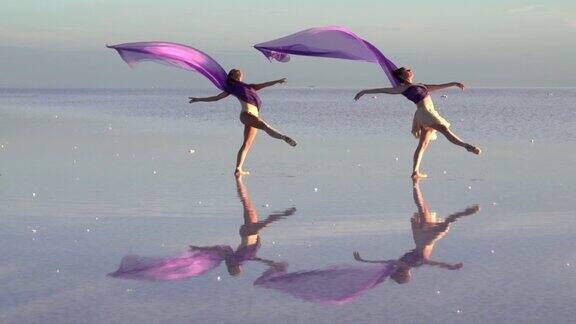 年轻的芭蕾舞者在盐湖上用彩色薄纱跳舞