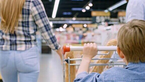 男孩和父母在超市里推着购物车奔跑