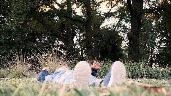 日落时分一个小男孩坐在公园的草地上