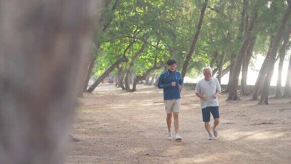 夏日清晨4K亚洲老人和成年儿子一起在海滩上做运动