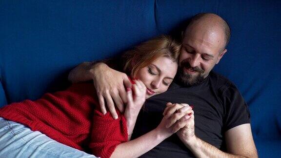 蓝色沙发上的一对温柔的夫妇正在温柔地拥抱着