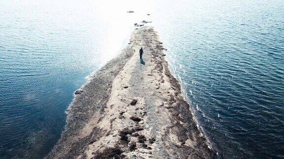 一个人走在荒凉的沙滩上在海洋的交汇处到达他旅程的终点4k鸟瞰图