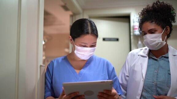 医疗工作者在医院戴着口罩行走和使用数字平板电脑