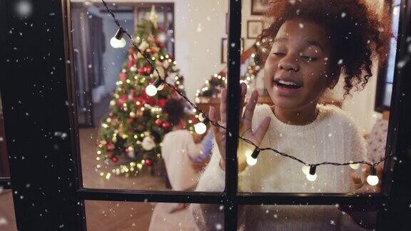 快乐的女孩一边看着窗外初雪飘落一边构思着冬天和圣诞节的情景