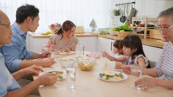 亚洲大家庭在家里的餐桌上一起吃午餐年迈的爷爷奶奶、年轻的夫妇和年幼的女儿们感到幸福在家里享受美食活动关系