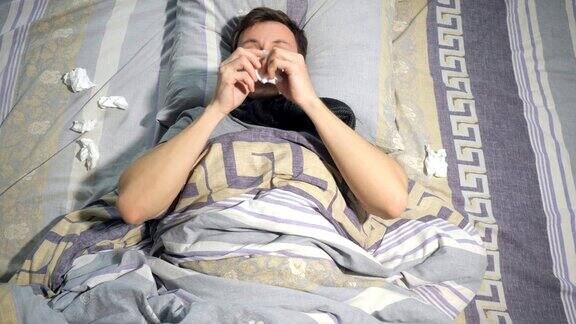 一个患流感流鼻涕的病人躺在家里的沙发上用纸巾擦鼻子