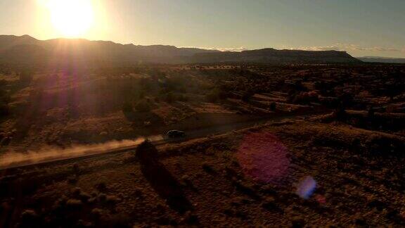 航拍:金色夕阳下黑色SUV吉普车行驶在沙漠山谷的土路上