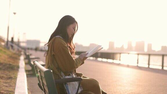 日落时分年轻女子在海滨公园看书第二部分
