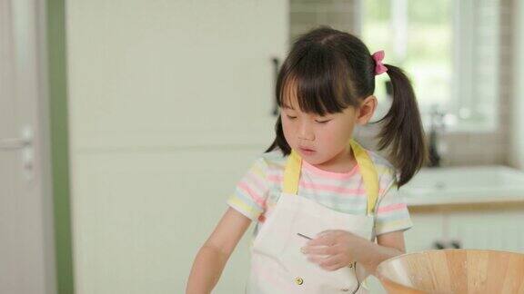 一个小女孩在家里的厨房里用面粉玩面团