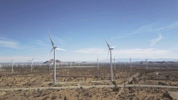 无人机快速飞越布满风力涡轮机的沙漠