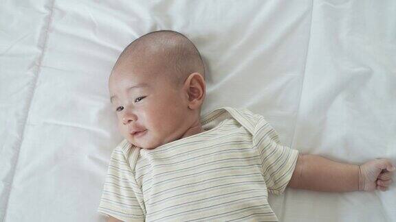 一个亚洲婴儿的肖像一个4个月大的男人独自躺在家里卧室的床上