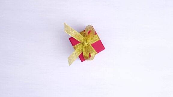 礼盒红色与金色丝带纺纱在粉红色的木材背景360度旋转无缝循环概念销售折扣价格圣诞假期和购物