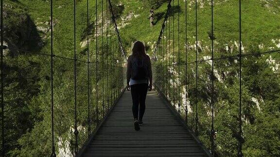 女探险家走在悬吊木桥上背影慢镜头