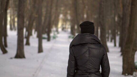 穿着黑色毛皮大衣的年轻快乐的女孩在公园的雪地上吹寒假快乐的女孩肖像在冬天的公园她玩雪