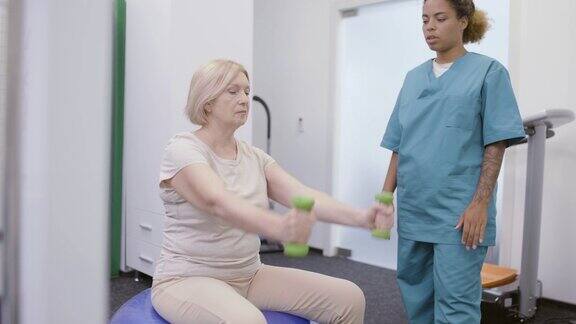 康复医生帮助病人哑铃运动在医院体育馆